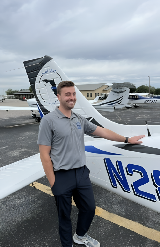 A smiling man standing next to a plane, with one hand placed on the aircraft.